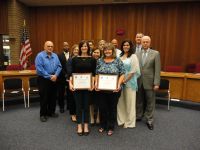 	 people posing for group photo, two people in front holding awards